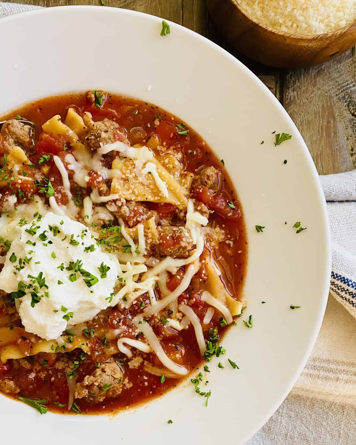 white bowl of lasagna soup topped with ricotta cheese