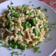 A bowl of pasta with peas, parma ham and asparagus.