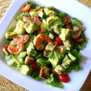 A caesar salad with grilled shrimp in a white bowl.