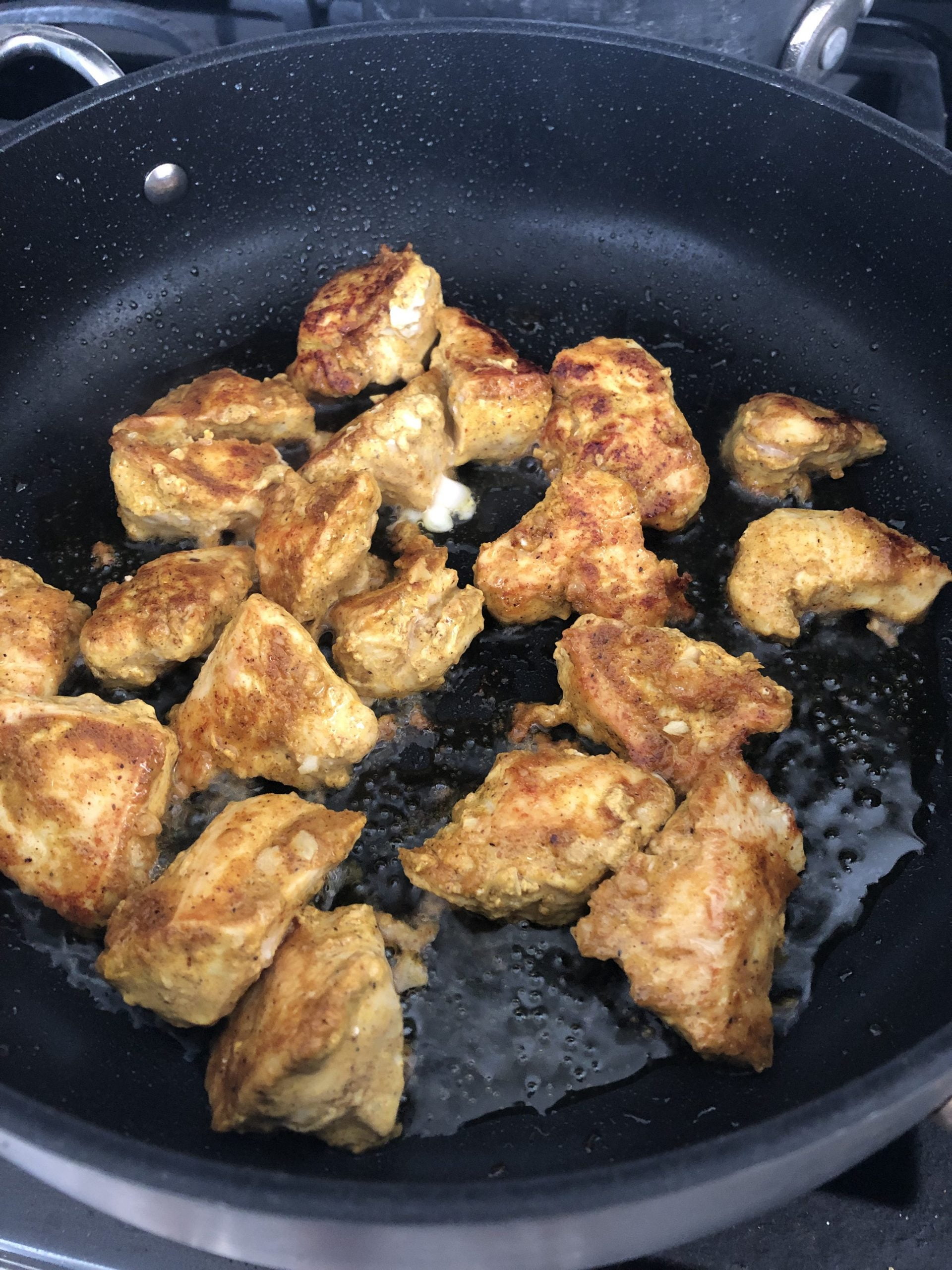 Sauteing chicken cubes in a pan.
