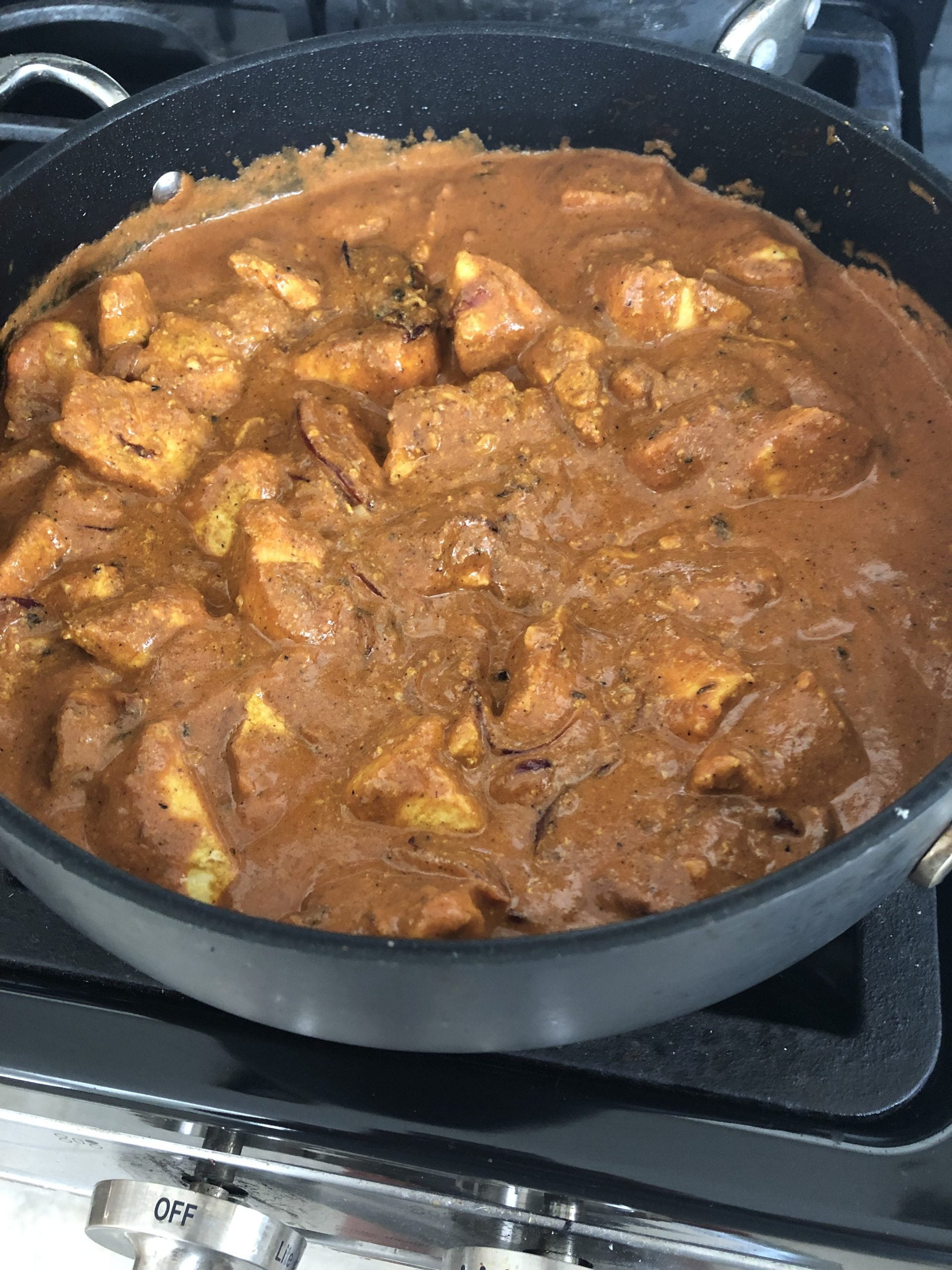 Simmering butter chicken on the stovetop.