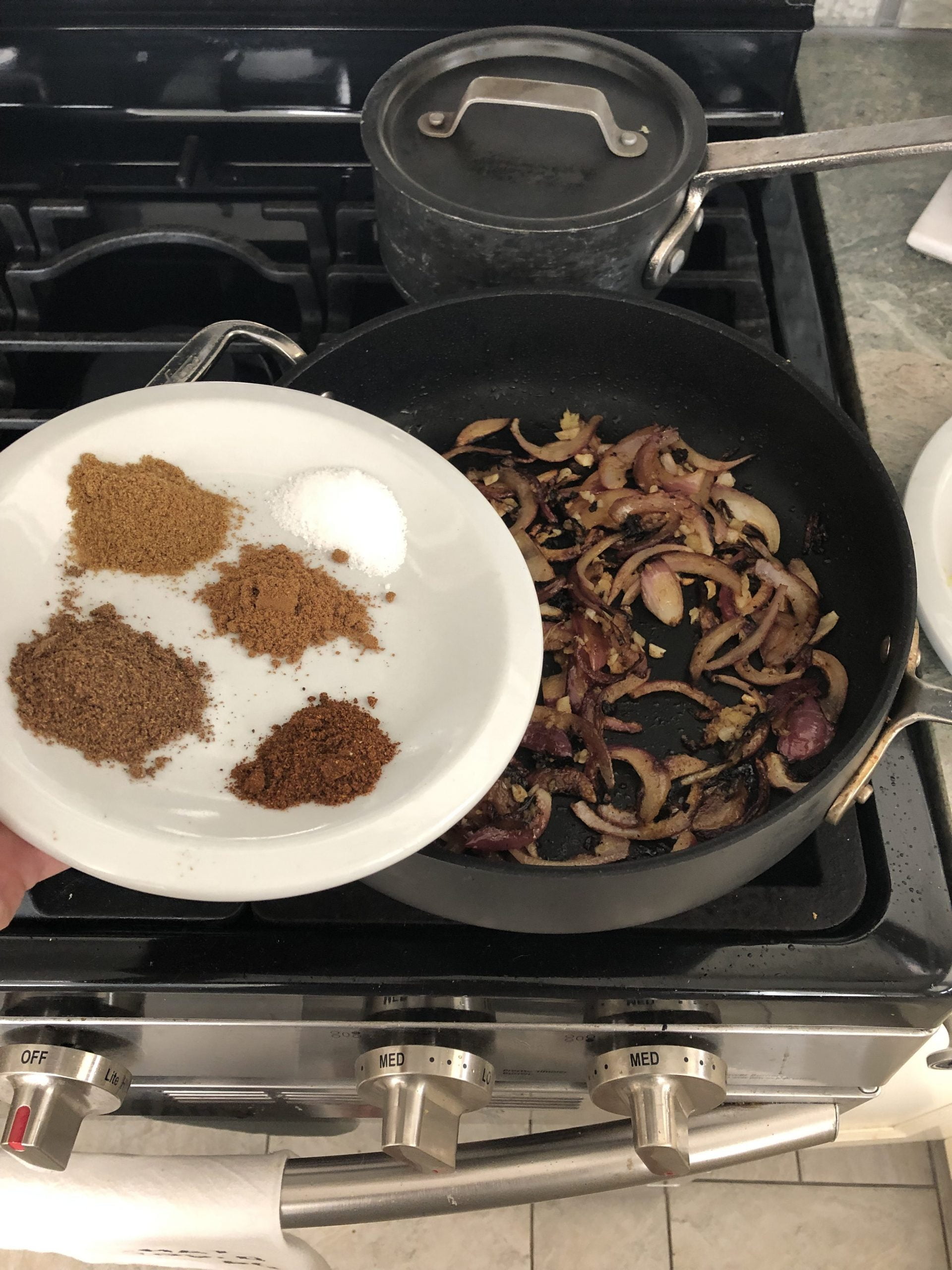 Spices on a plate and sauteed red onions.