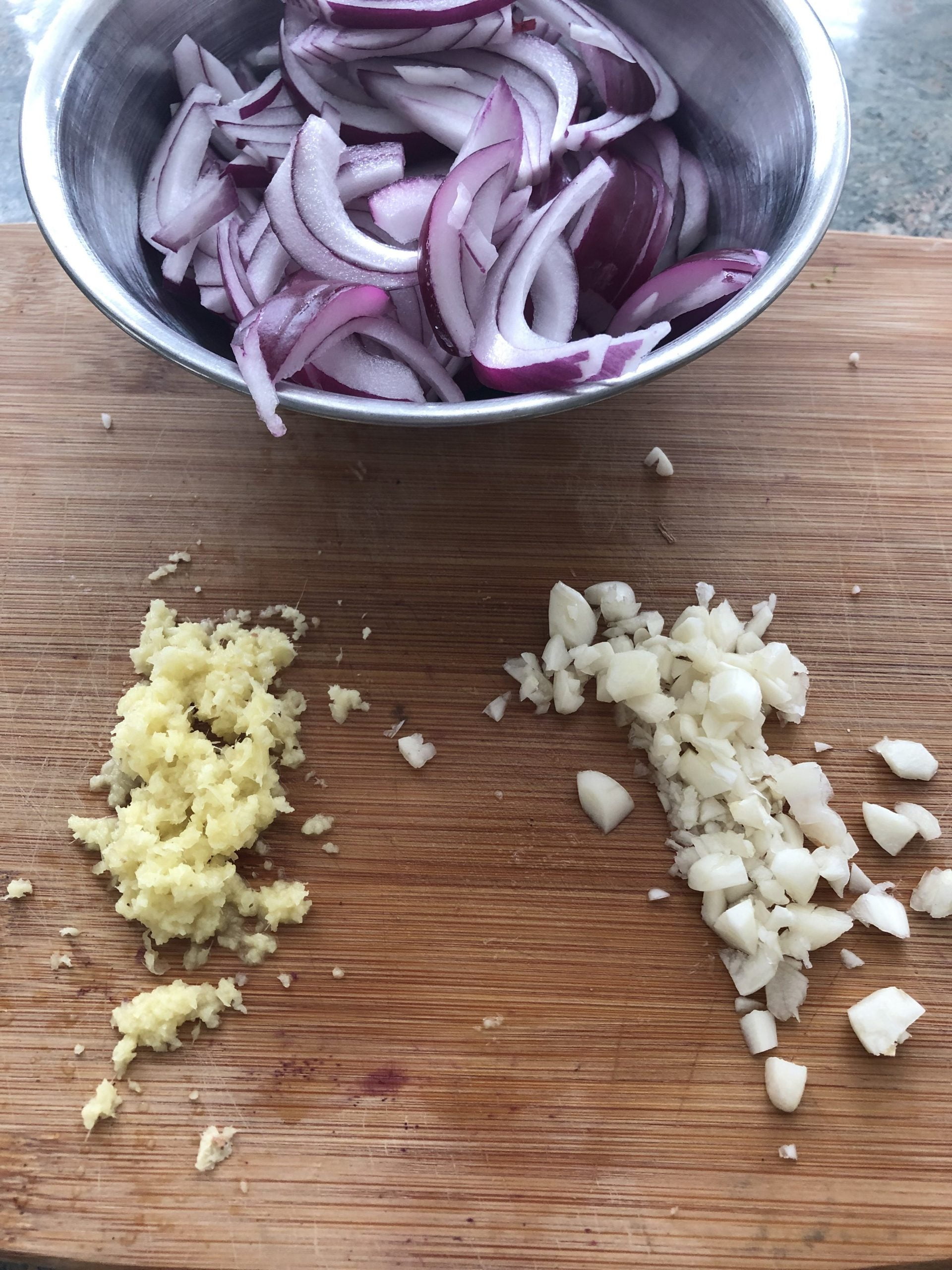 Sliced red onions, chopped onions and minced garlic on a cutting board.