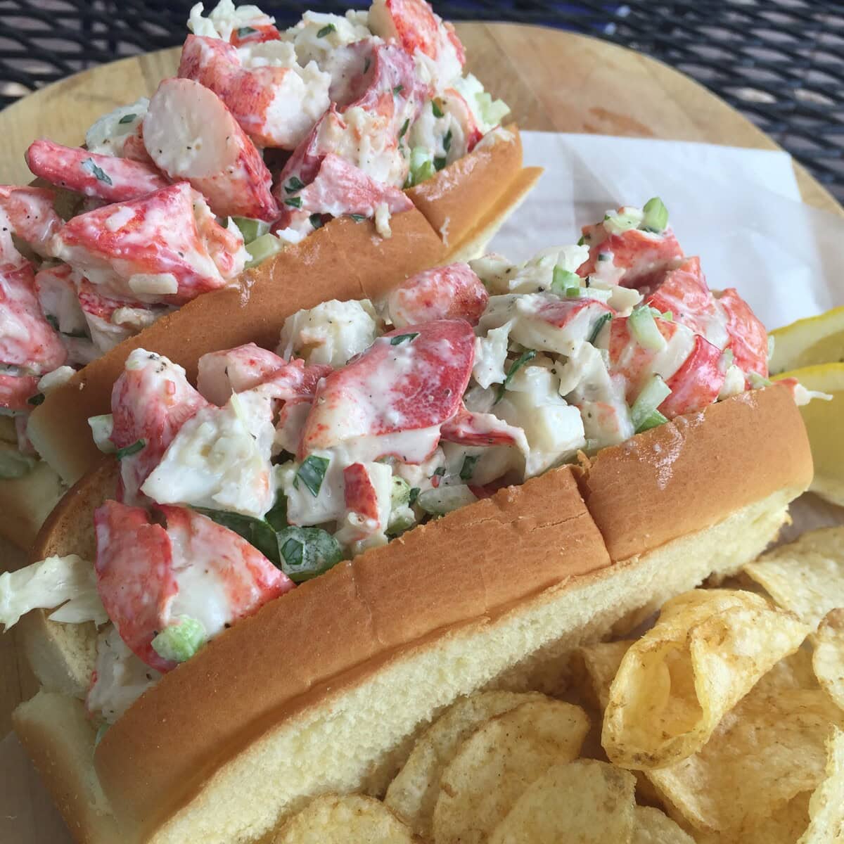 Two lobsters rolls with potato chips.