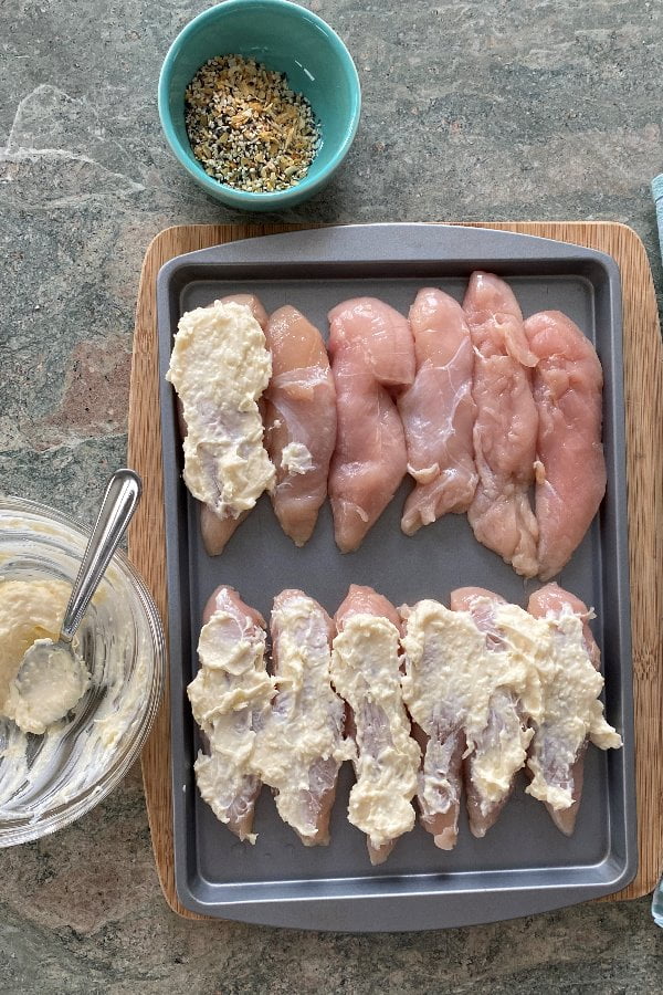 spreading chicken with parmesan cheese and mayo mixture