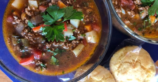 bowl of hearty hamburger soup with cornbread muffins