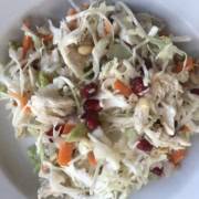 A white bowl of cole slaw with chicken.