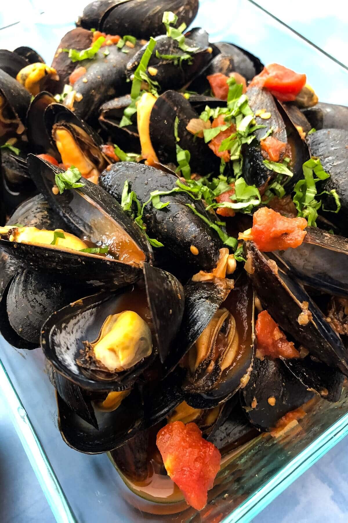 Mussels with red sauce in a storage container.