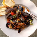 A bowl of mussels marinara with bread and butter.