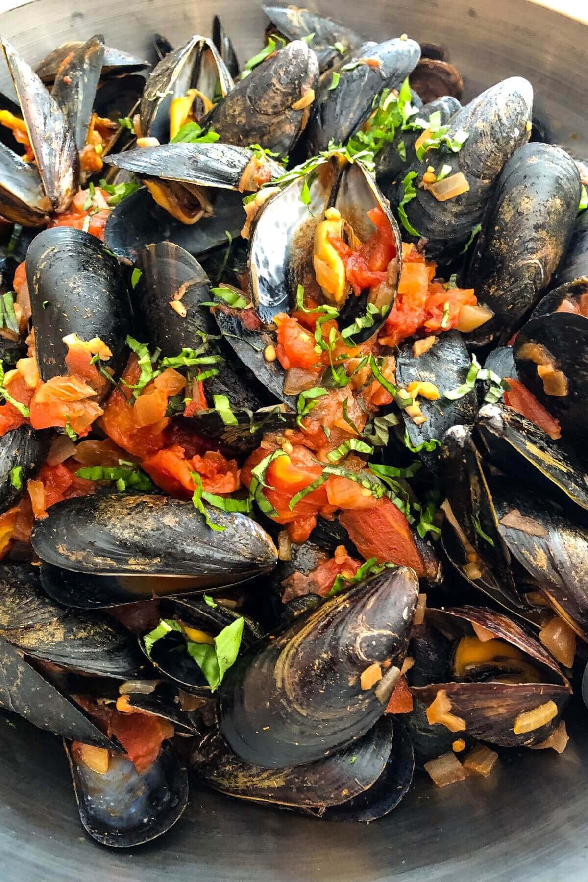 Mussels in marinara sauce in a large bowl.
