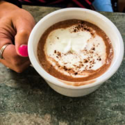 mug of hot cocoa with woman's hand holding it