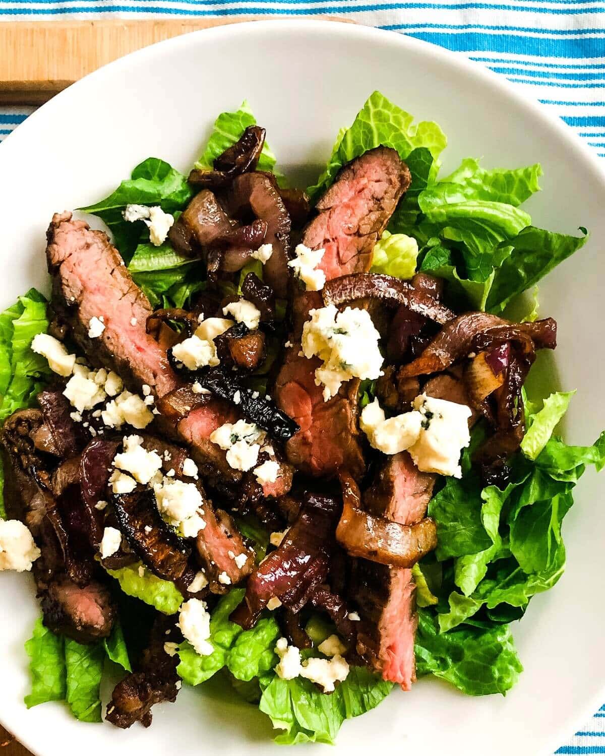 A skirt steak salad on a white plate.
