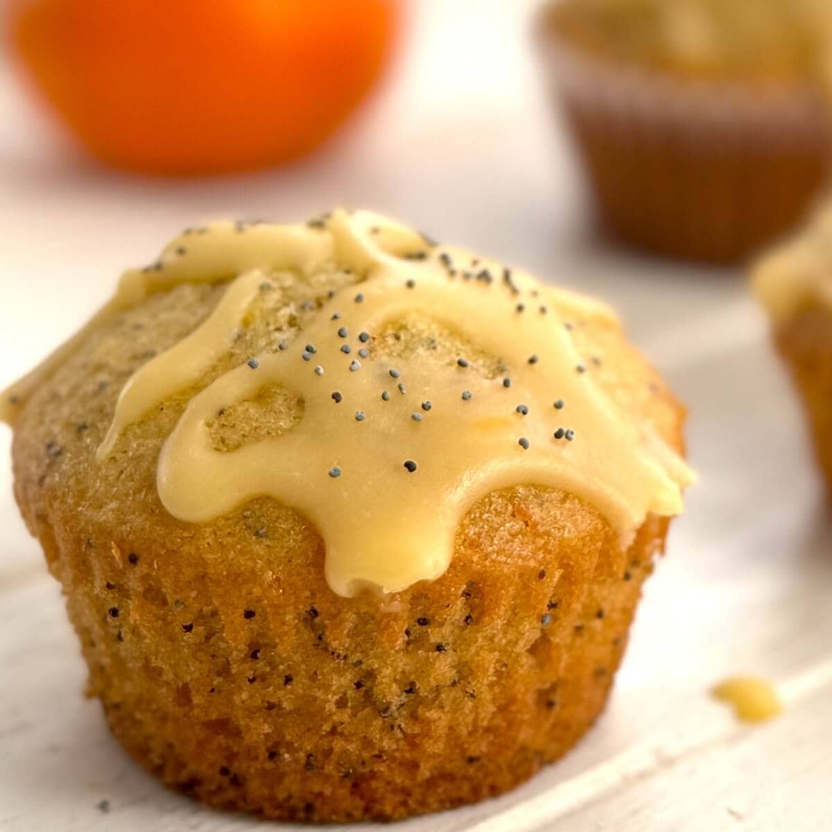 A single orange poppy seed muffin with glaze.