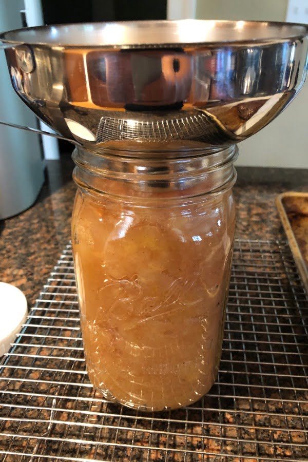 putting applesauce into glass jars with a wide mouth funnel