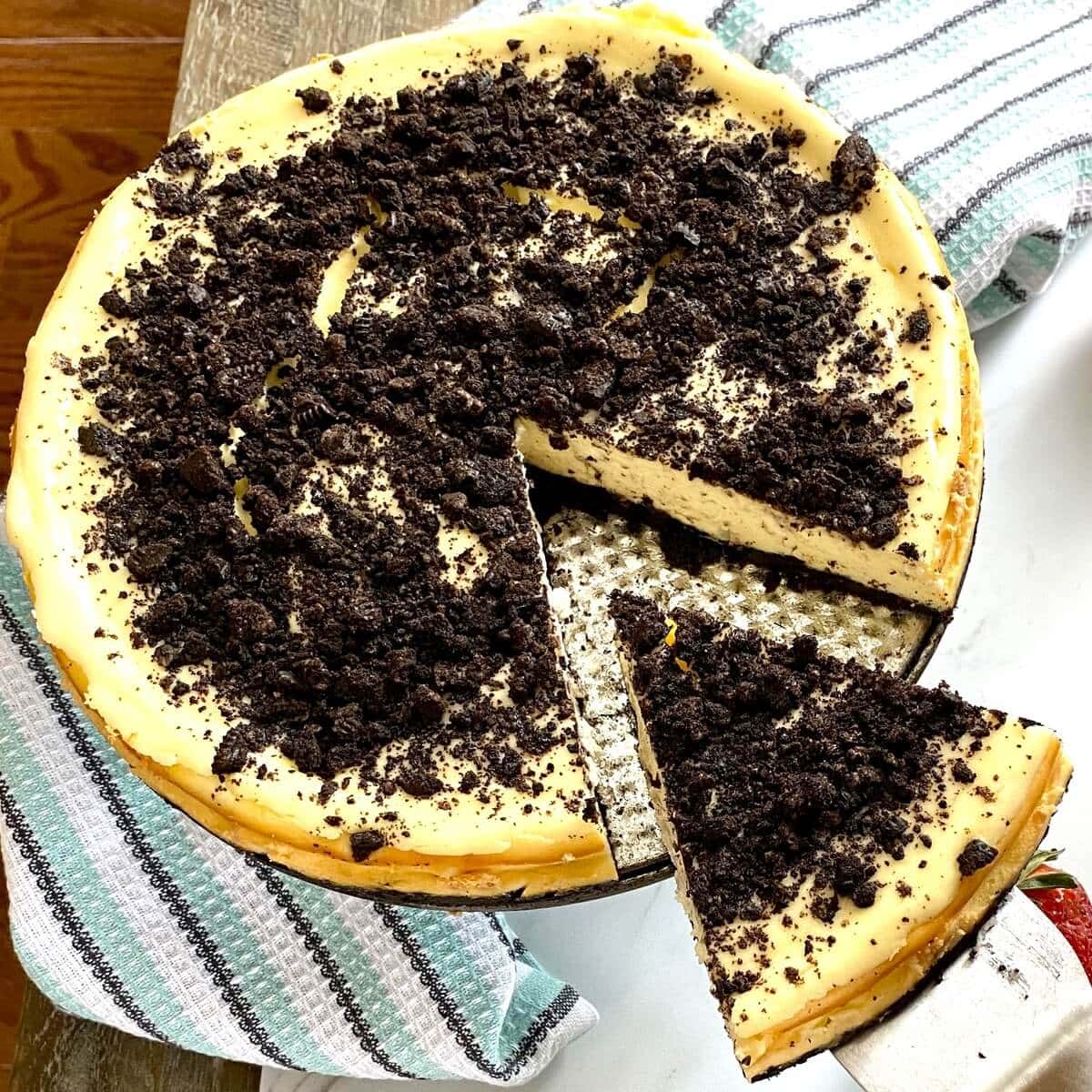 A whole Oreo cheesecake that has a slice cut out of it.