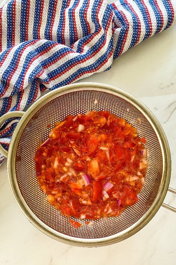 draining chopped tomatoes in a strainer