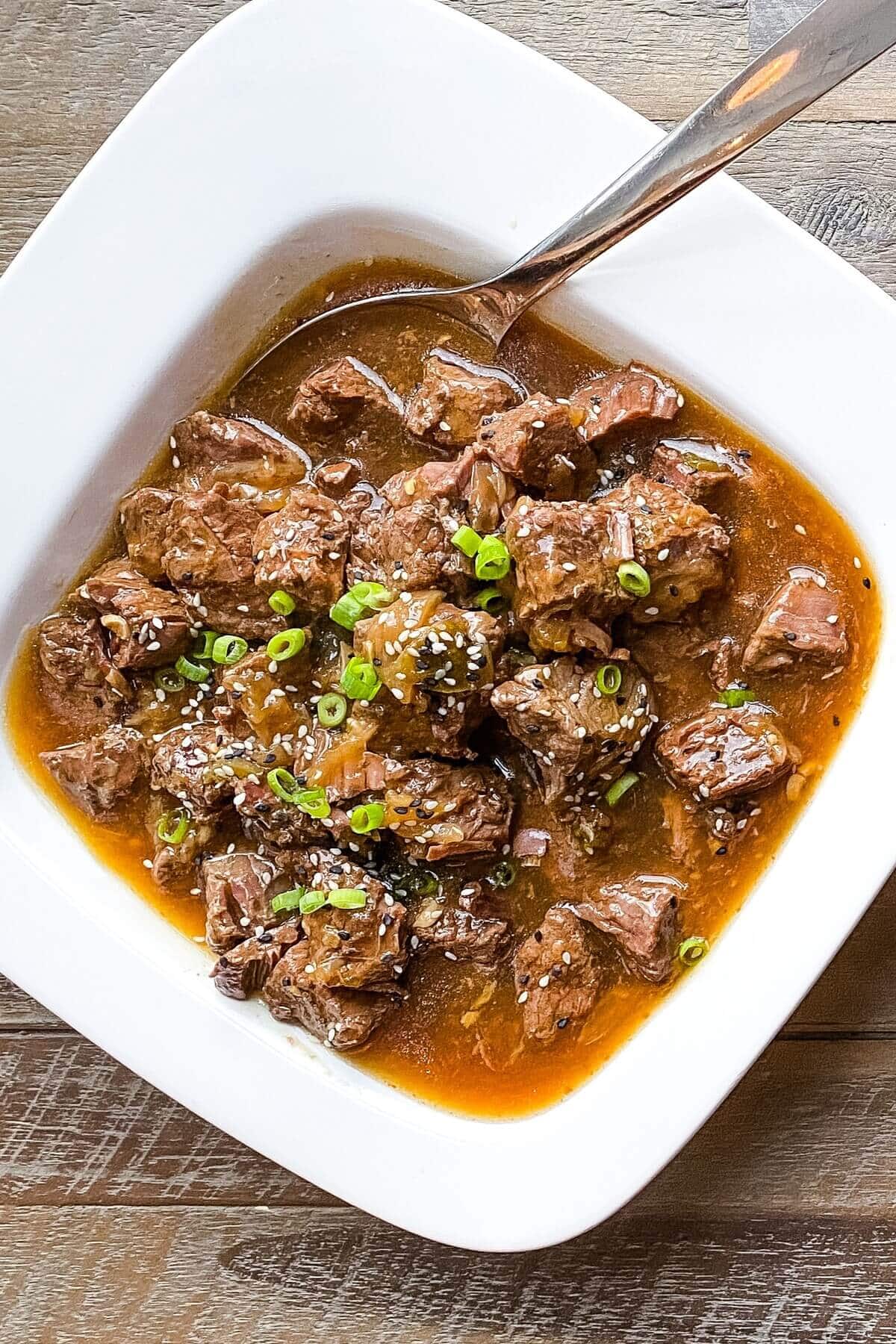 A large bowl of Asian beef stew with a spoon.