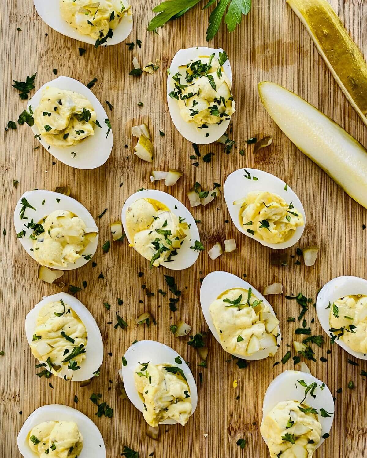 dill pickle stuffed hard boiled eggs on a cutting boad.