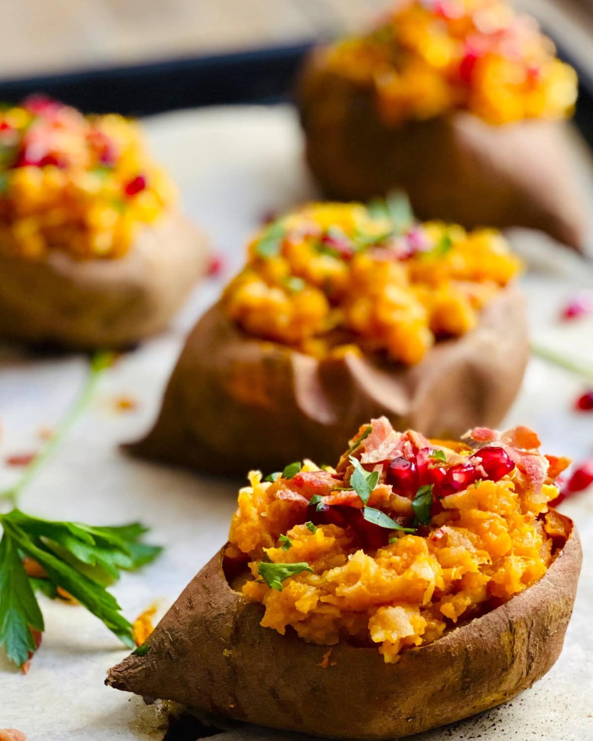 Four apple stuffed sweet potatoes on a baking sheet.