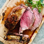 sliced prime rib roast on a cutting board with 1 rib bone