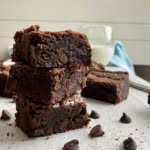 3 brownies stacked on top of each with a glass of milk