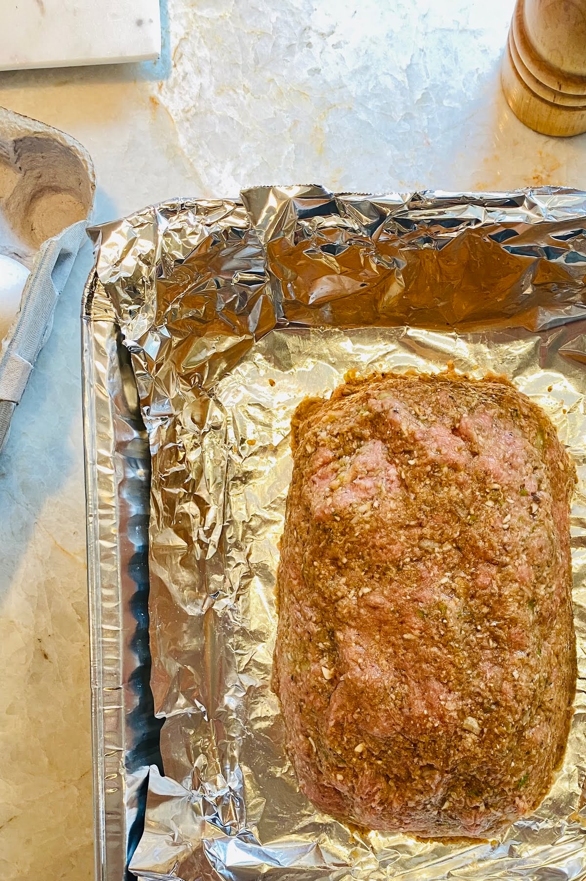 An unbaked turkey meatloaf in a foil lined pan.