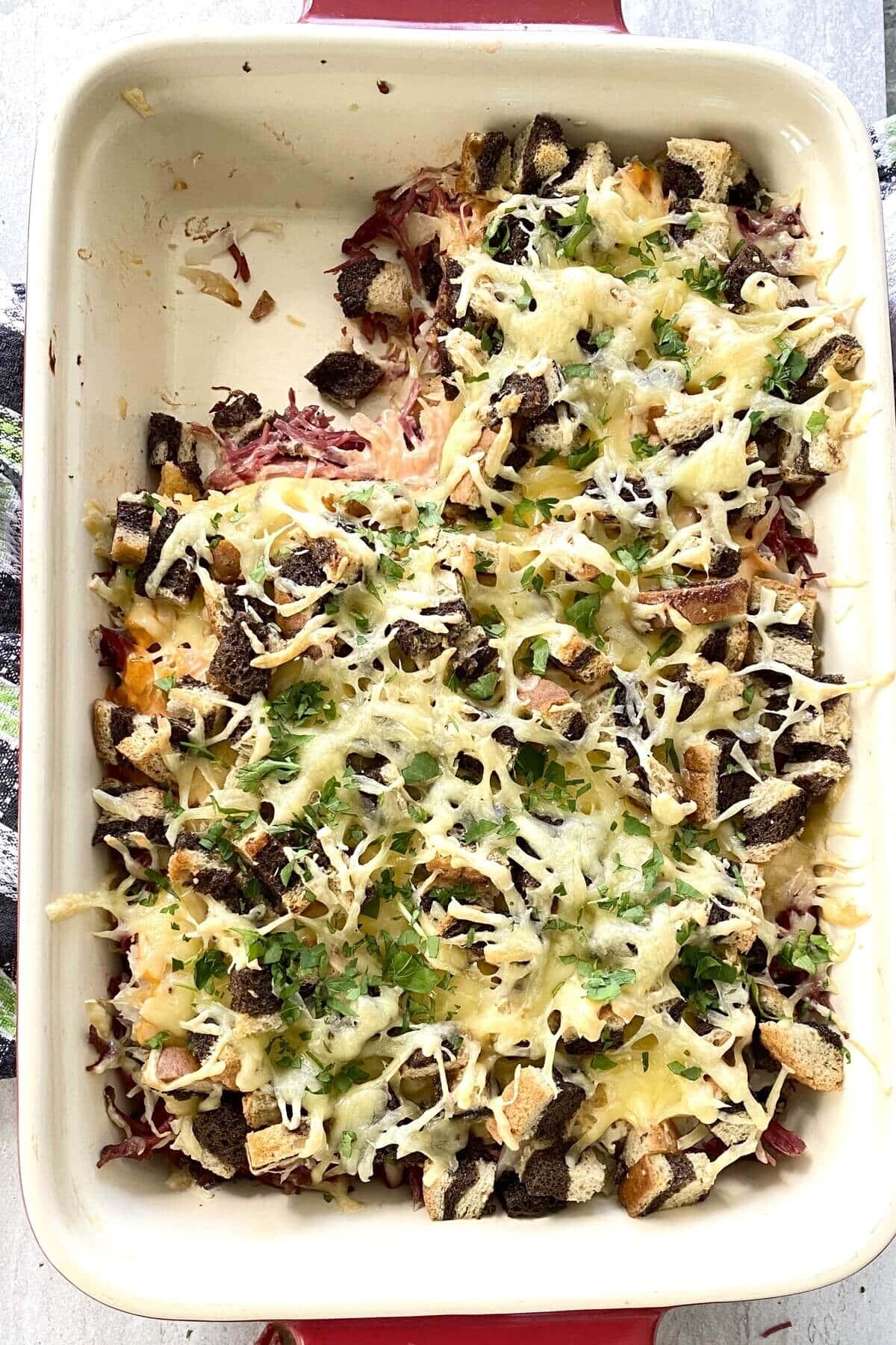 A reuben casserole bake with one piece missing.