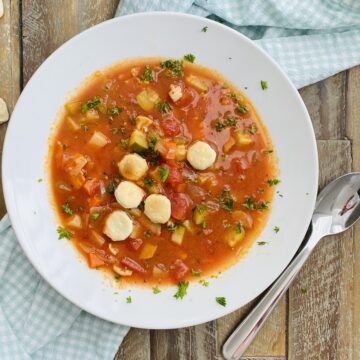 A bowl of Manhattan clam chowder with oyster crackers.