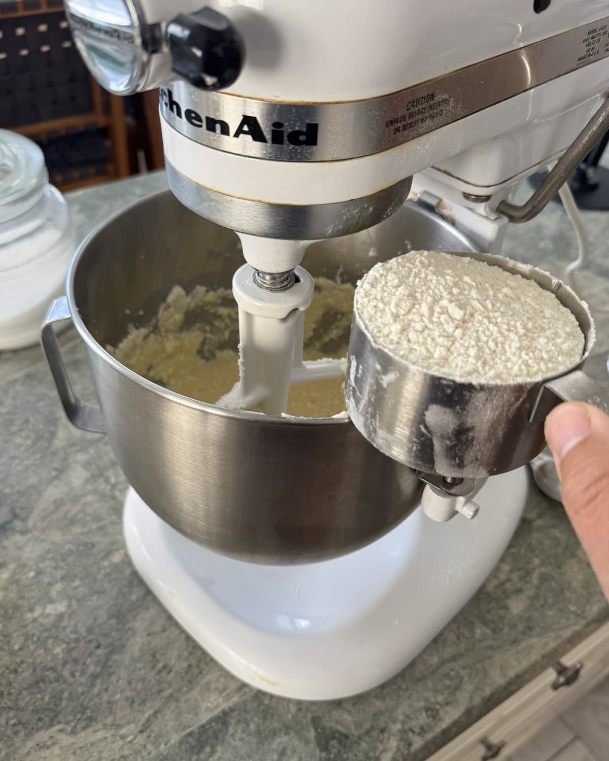 Adding flour to a mixing bowl.