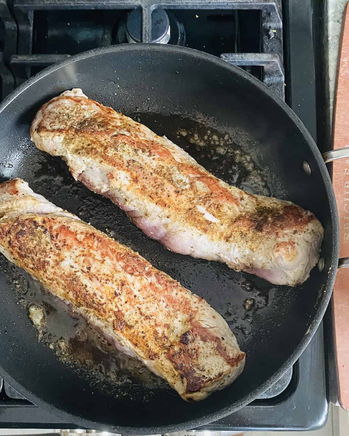 Searing 2 pork tenderloins in a cast iron skillet.