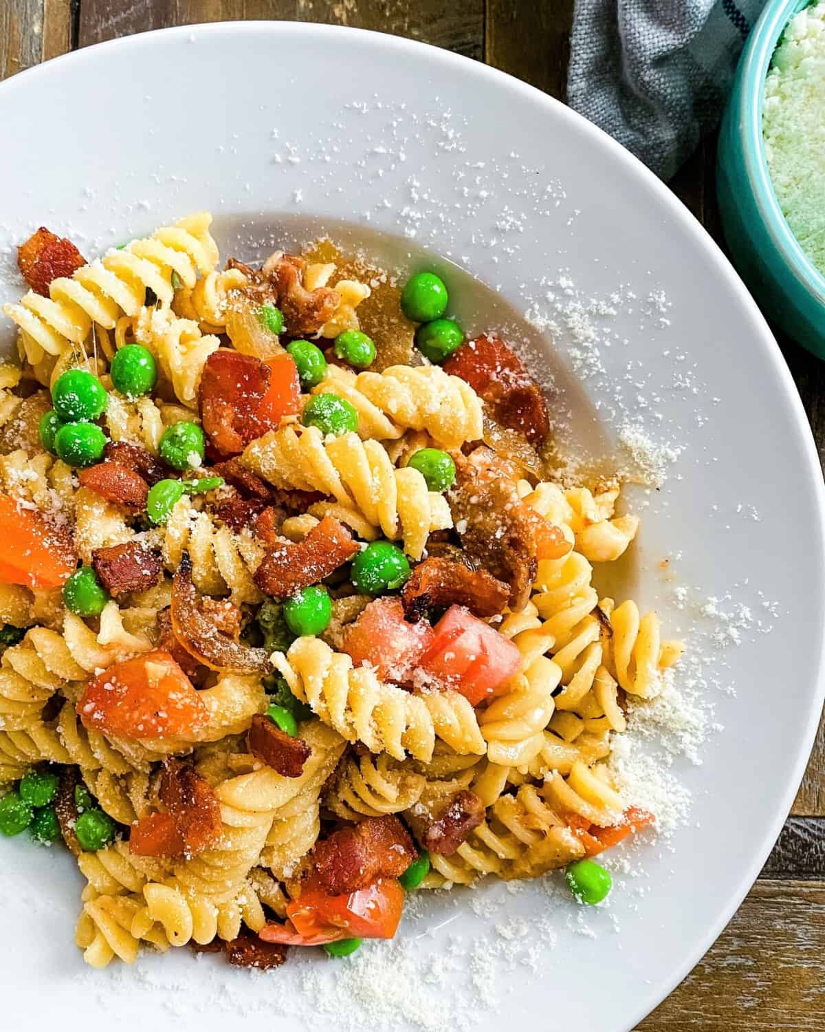 bowl of pasta with bacon, tomatoes, onions and peas