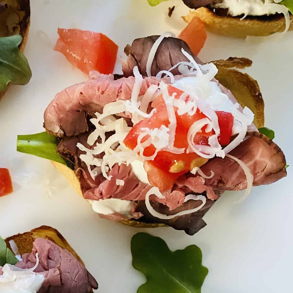 1 crostini topped with roast beef and shredded cheese