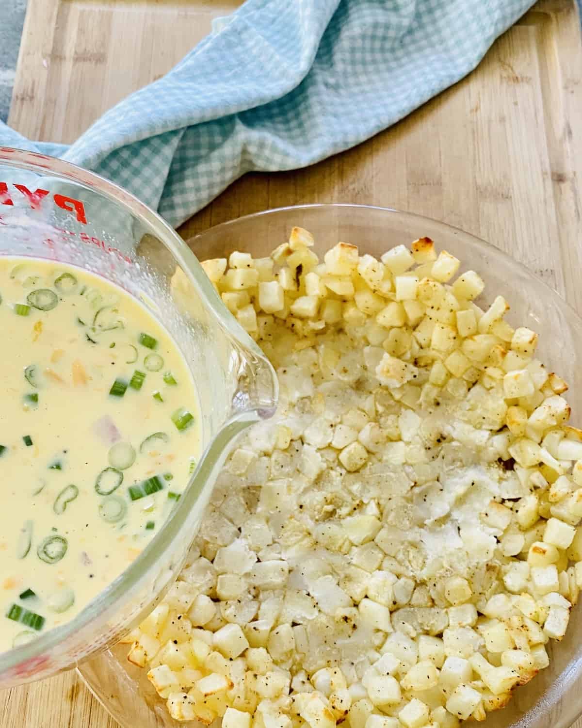 Pouring quiche filling into hash brown crust.