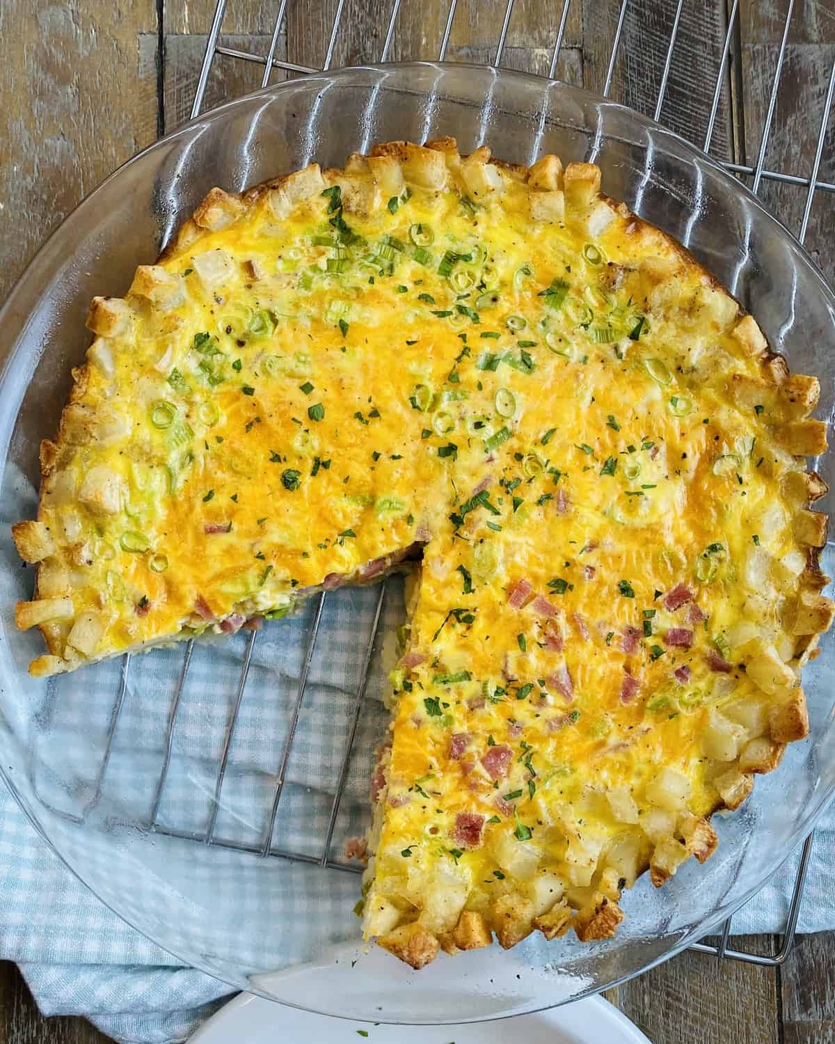 A hash brown crust quiche with a slice missing.