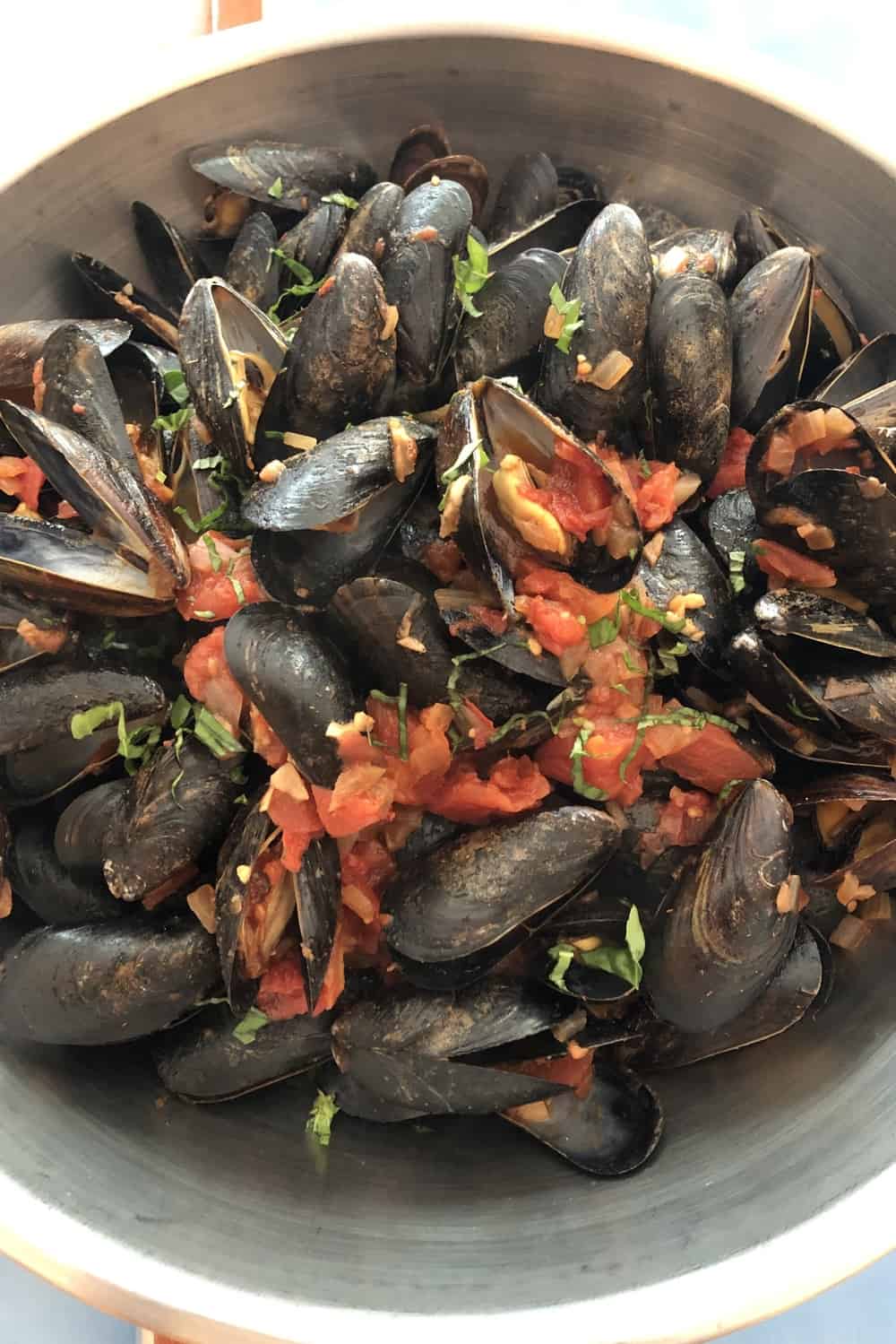 big bowl of cooked mussels with a homemade spicy marinara sauce