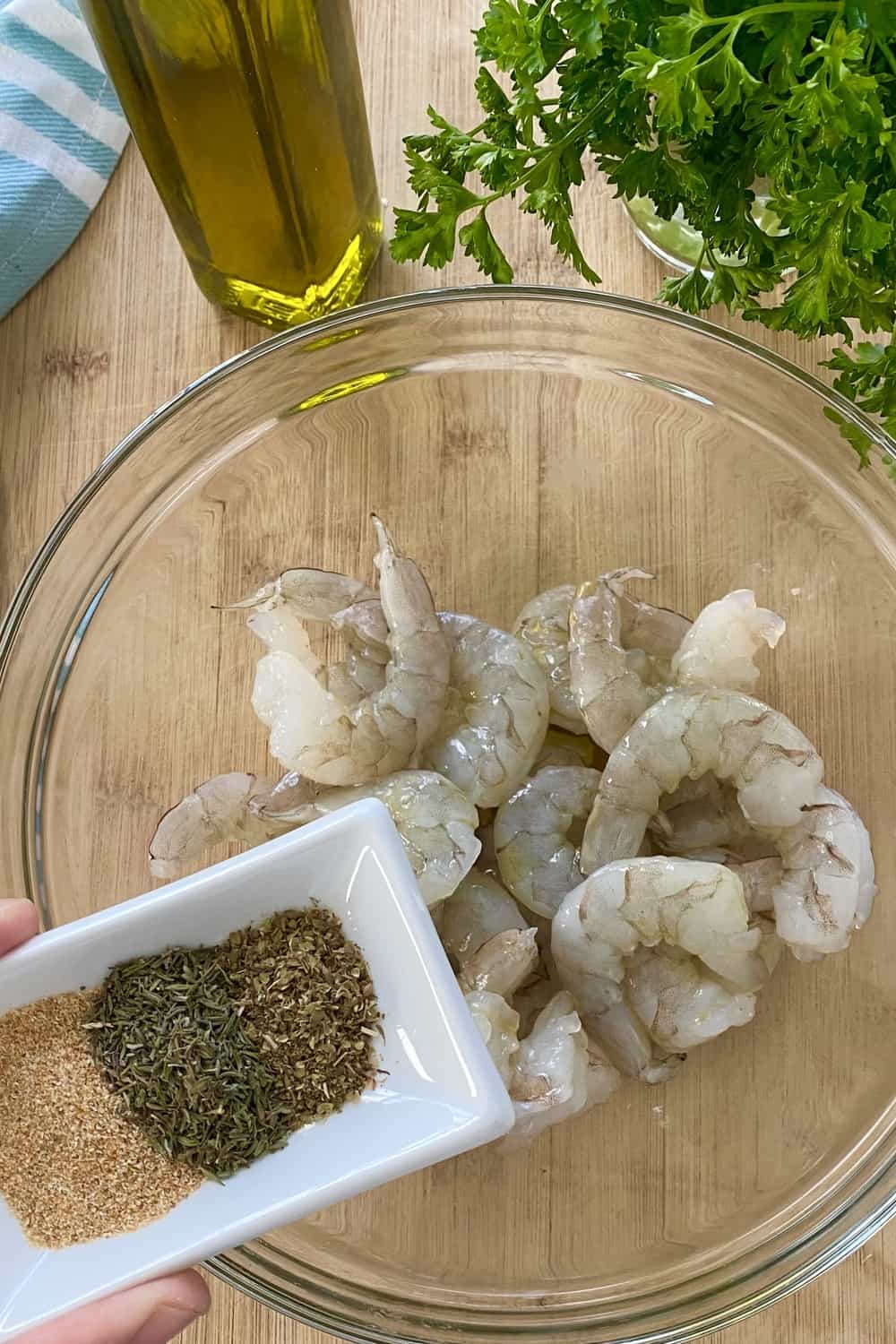A bowl of raw shrimp and a small dish with spices.