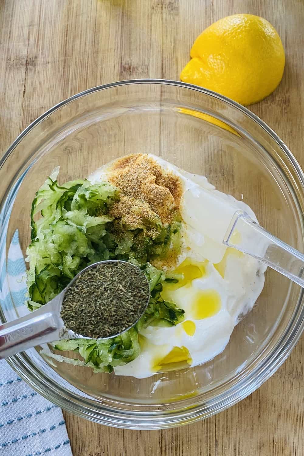 Making tzatziki sauce with sour cream, shredded cumbers and seasonings.