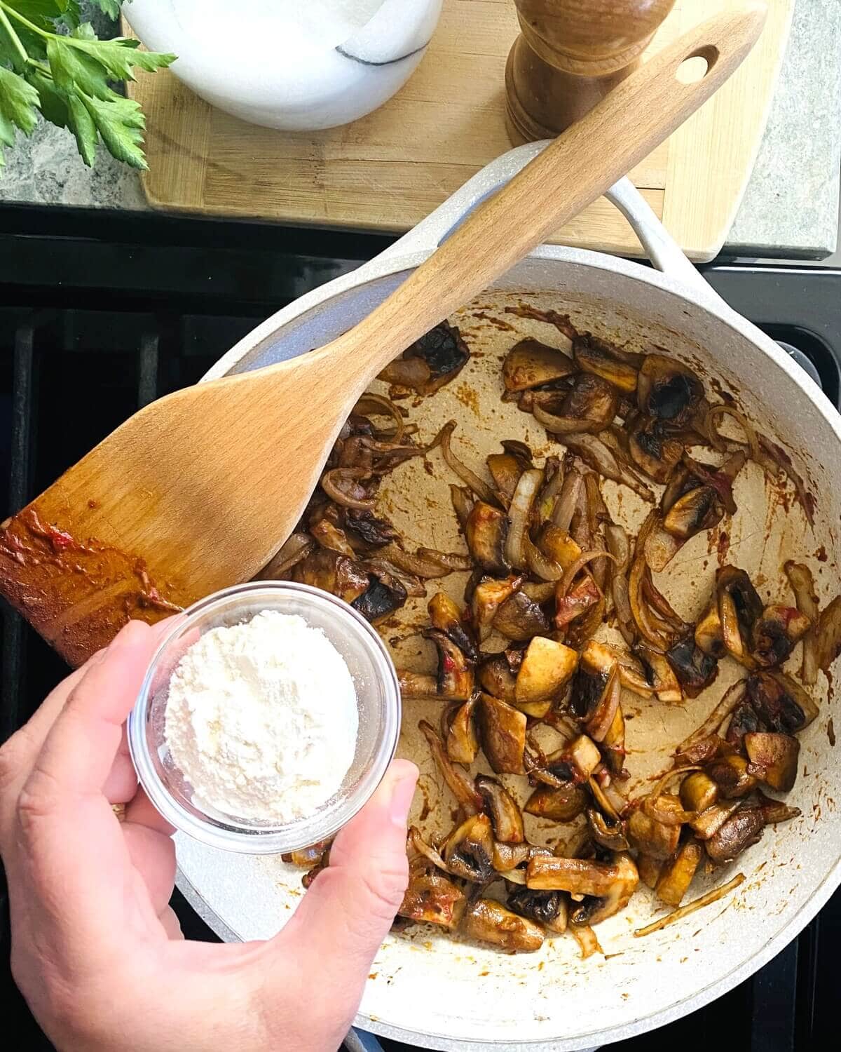 Adding flour to sauteed mushrooms and onions.