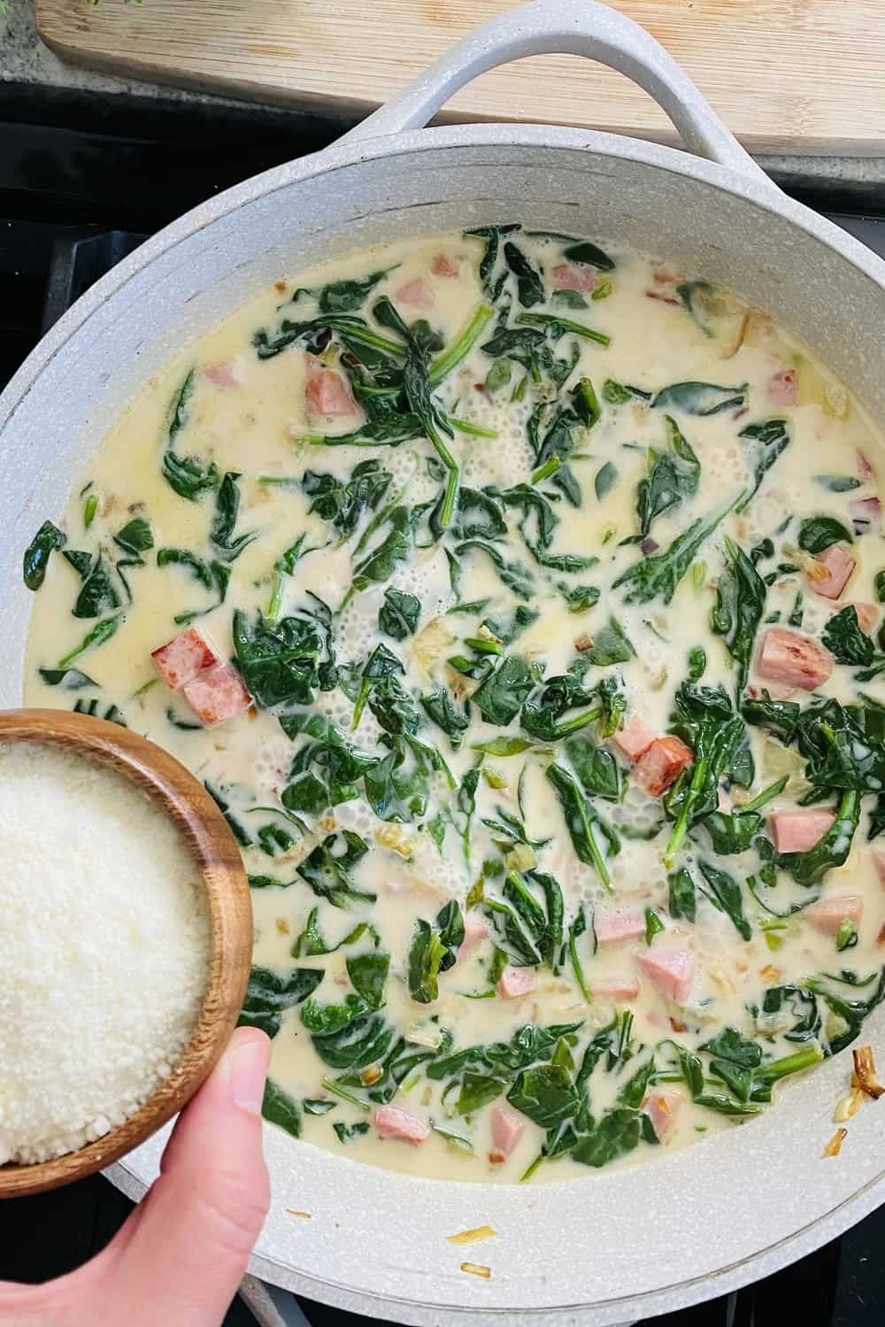 adding Parmesan cheese to sauce