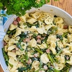 tortellini in a sauté pan with sauteed ham, spinach and asparagus