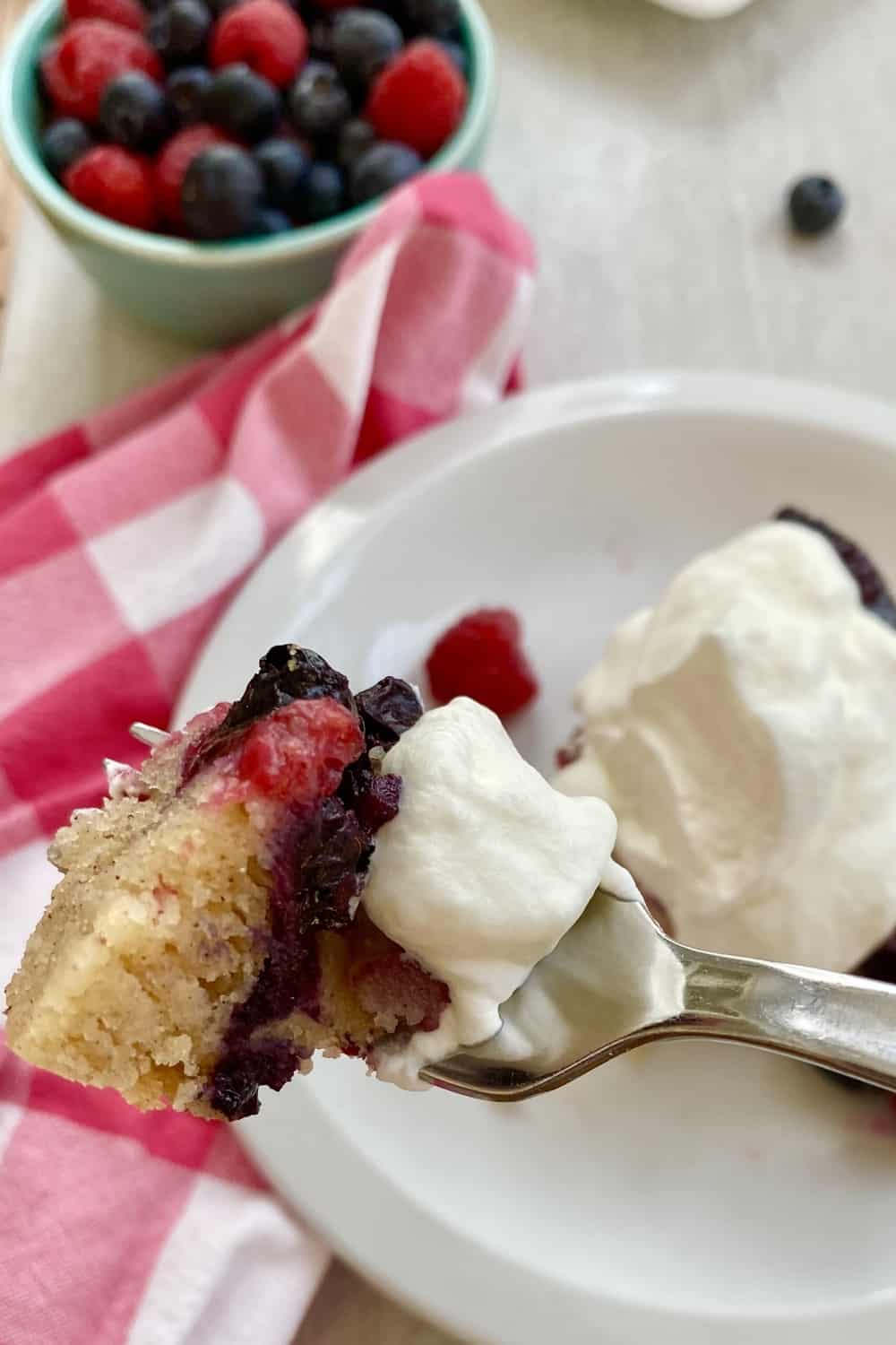 fork with berry cake and whipped cream