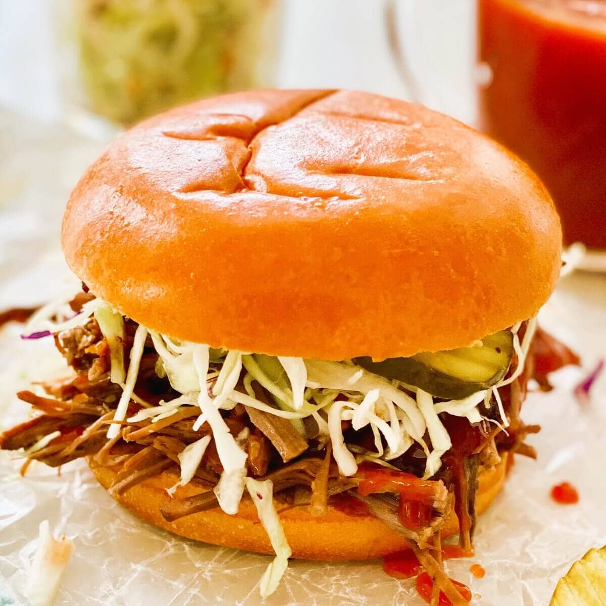 A beef brisket sandwich with barbecue sauce, cole slaw and pickles.