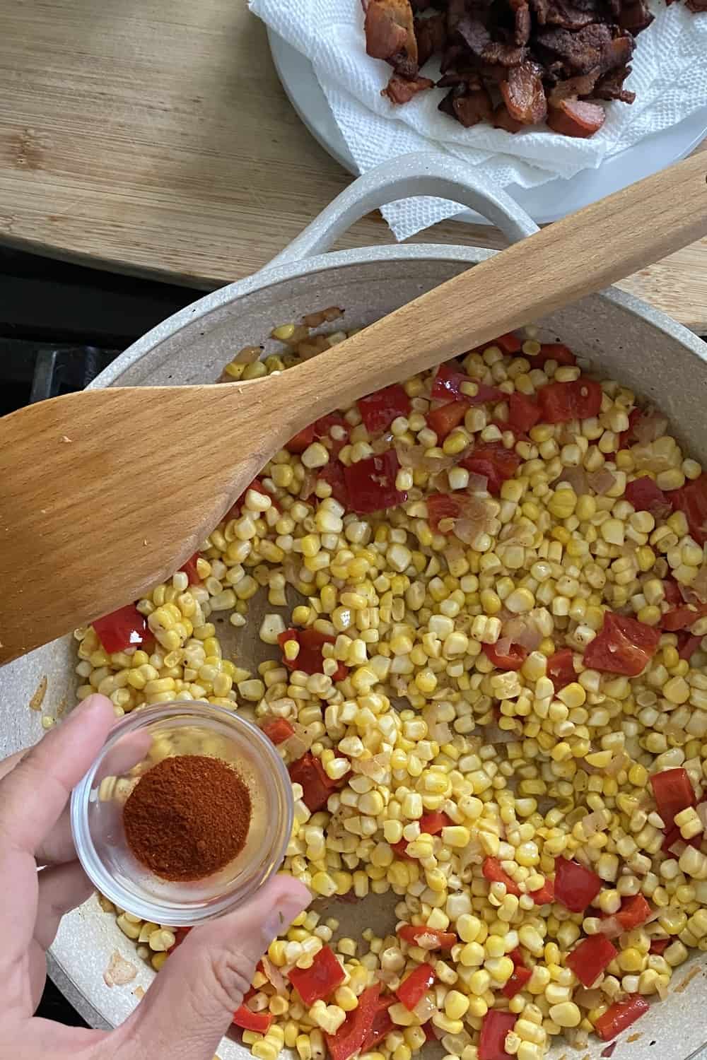 Adding smoked paprika to sweet corn salad sauté.