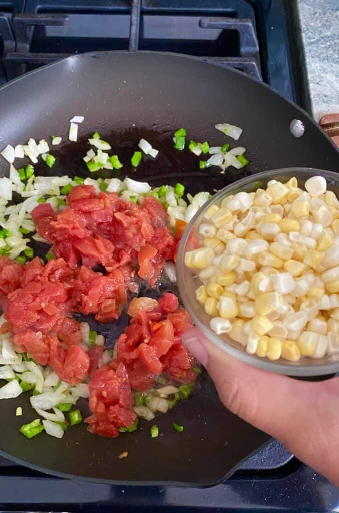 adding sweet corn to tomato sauté