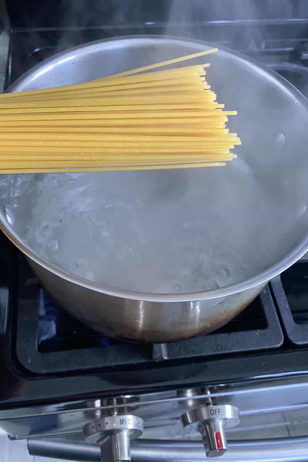 adding fettuccine to boiling water in a pot