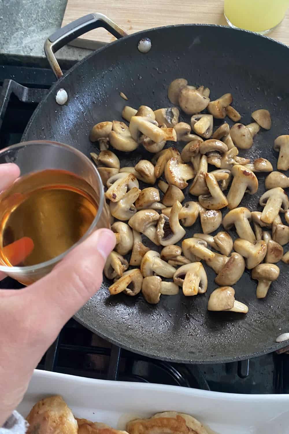 adding marsala to a pan of sauteed mushrooms.