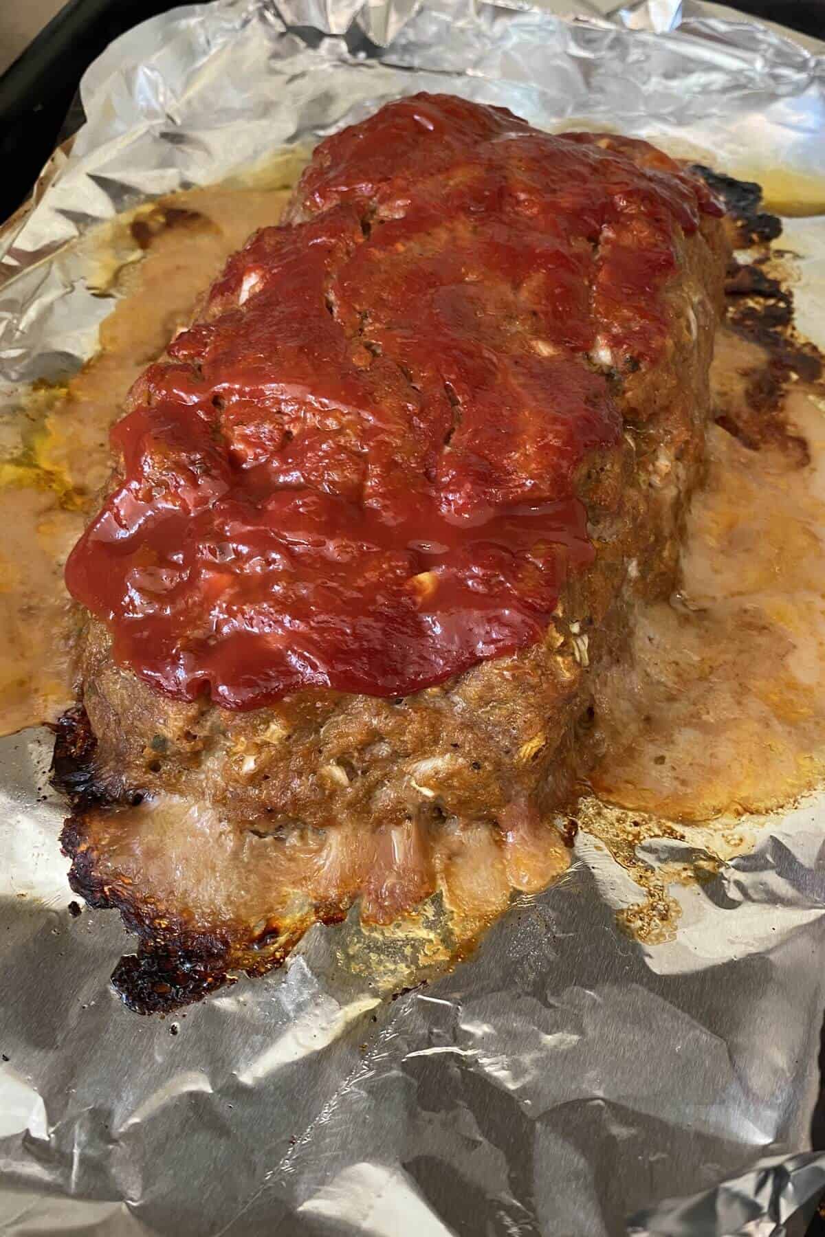 a baked meatloaf on a foil lined baking sheet.