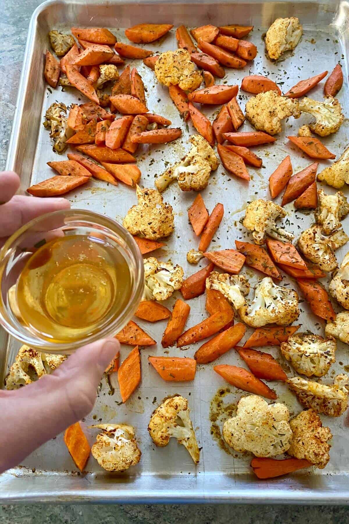 adding honey to roasted carrots and cauliflower.