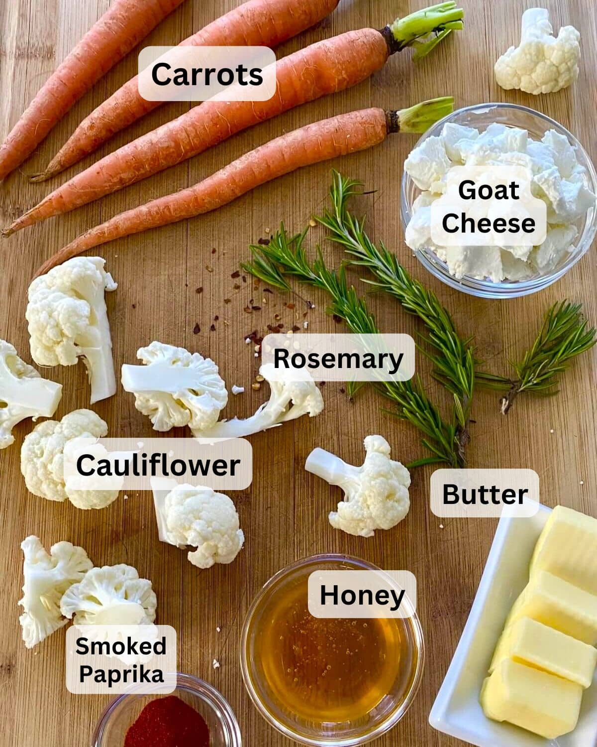 Carrots, cauliflower, goat cheese, butter, honey, rosemary, smoked paprika on a cutting board.