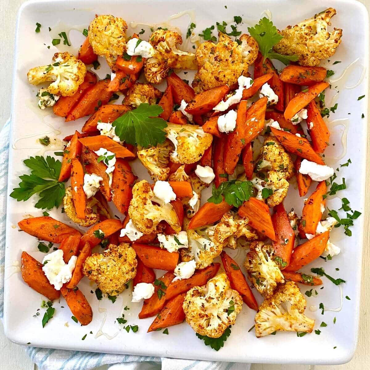 Roasted carrots and cauliflower with goat cheese on a plate.
